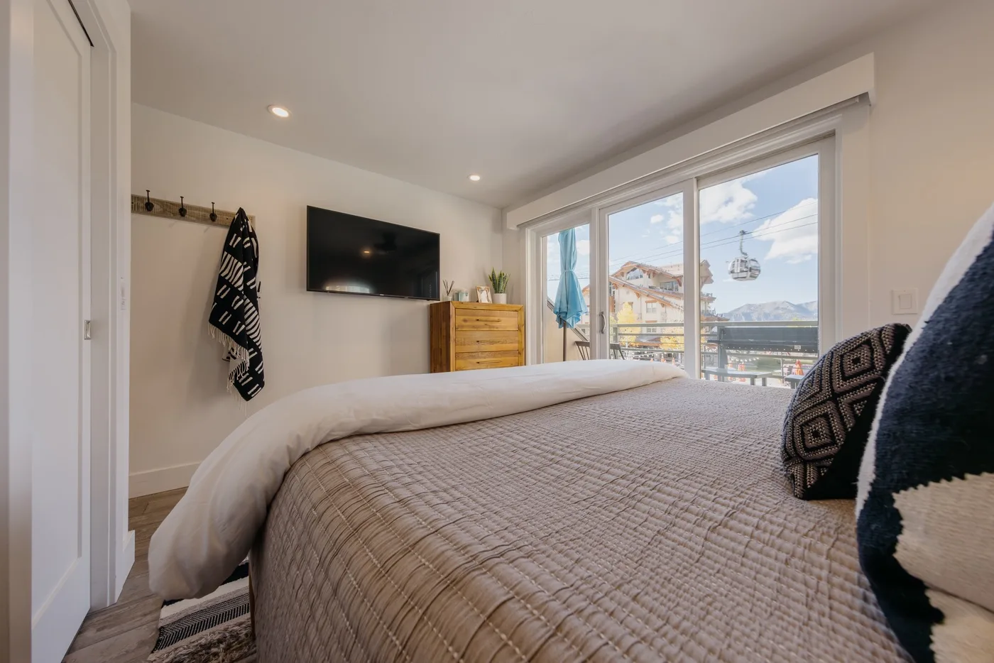 A bright bedroom with a neatly made bed and large windows overlooking the outdoors.