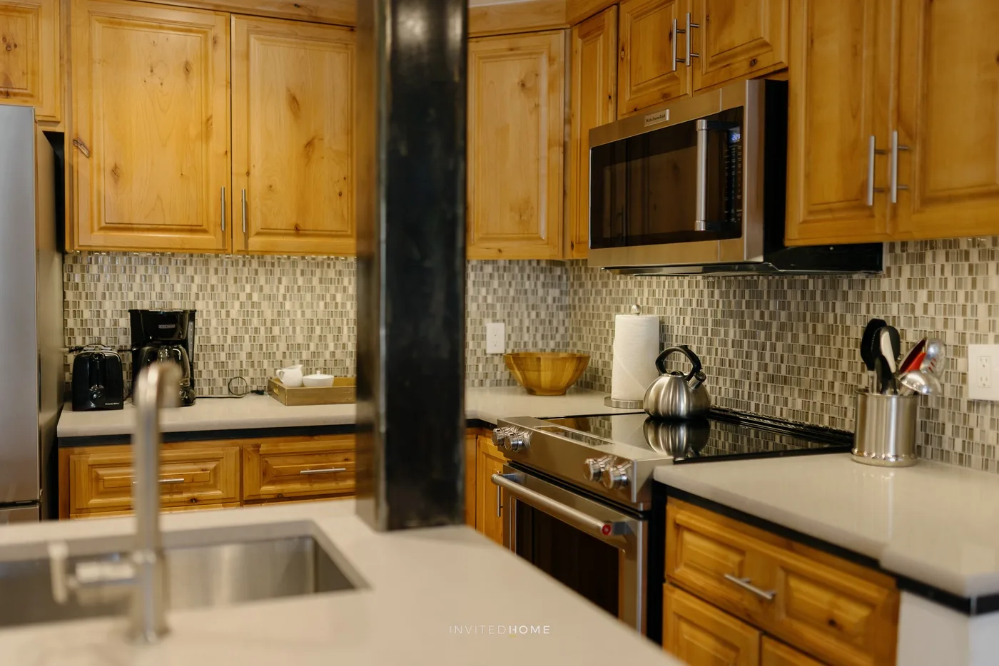 A wood-cabinet kitchen with a tiled backsplash and a central island.