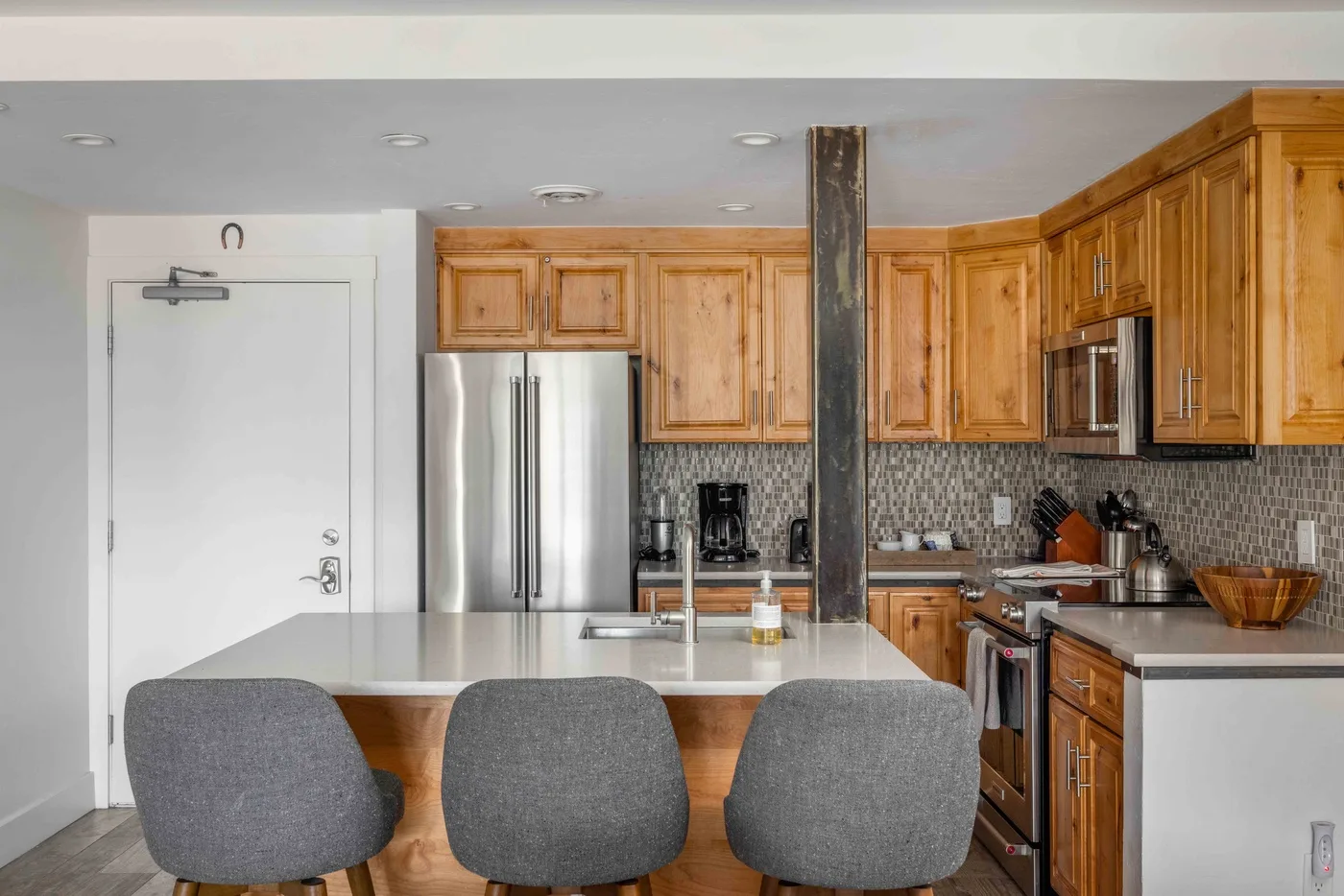 A kitchen with wooden cabinets, stainless steel appliances, and an island with seating.