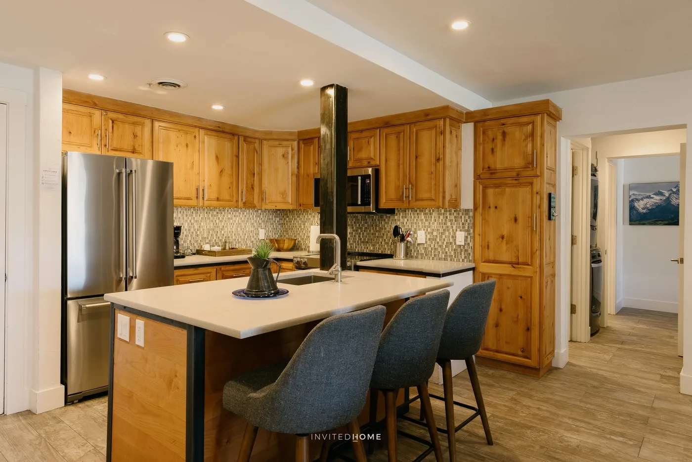 A kitchen with wooden cabinets, stainless-steel appliances, and seating at the island.