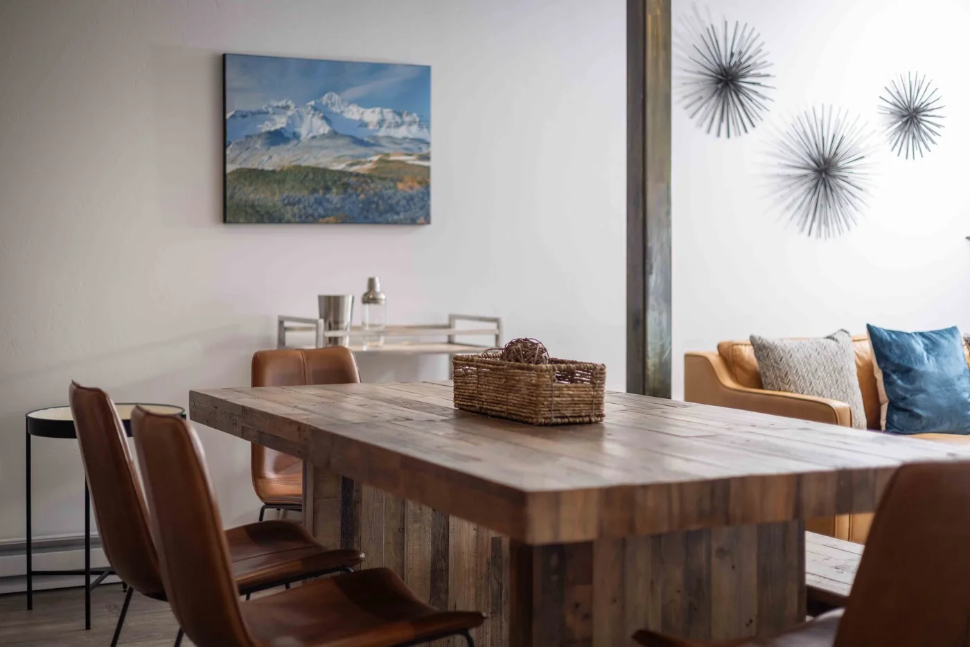 A dining area with a wooden table and chairs beside a sofa.