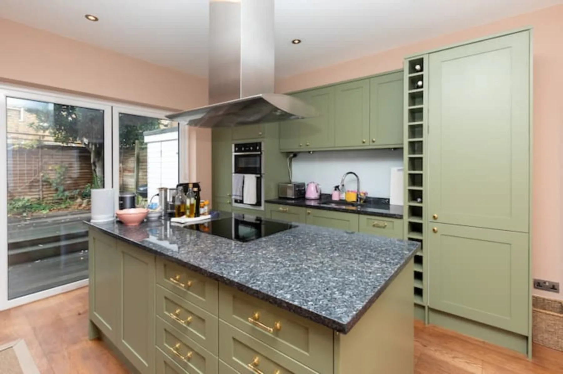 A kitchen with green cabinetry, a central island, and glass doors.
