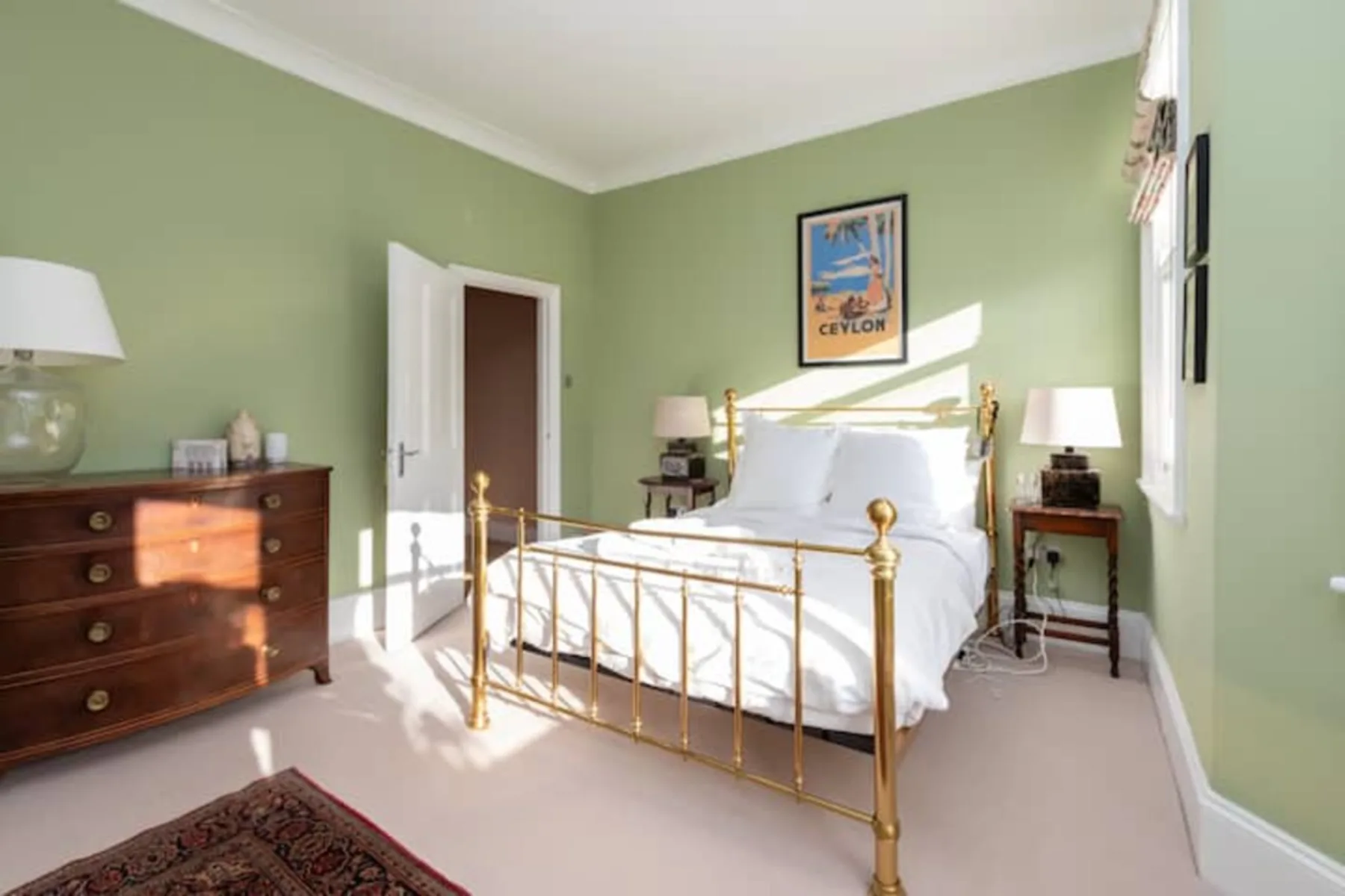 A bedroom with a white bed, green walls, and wooden furniture.