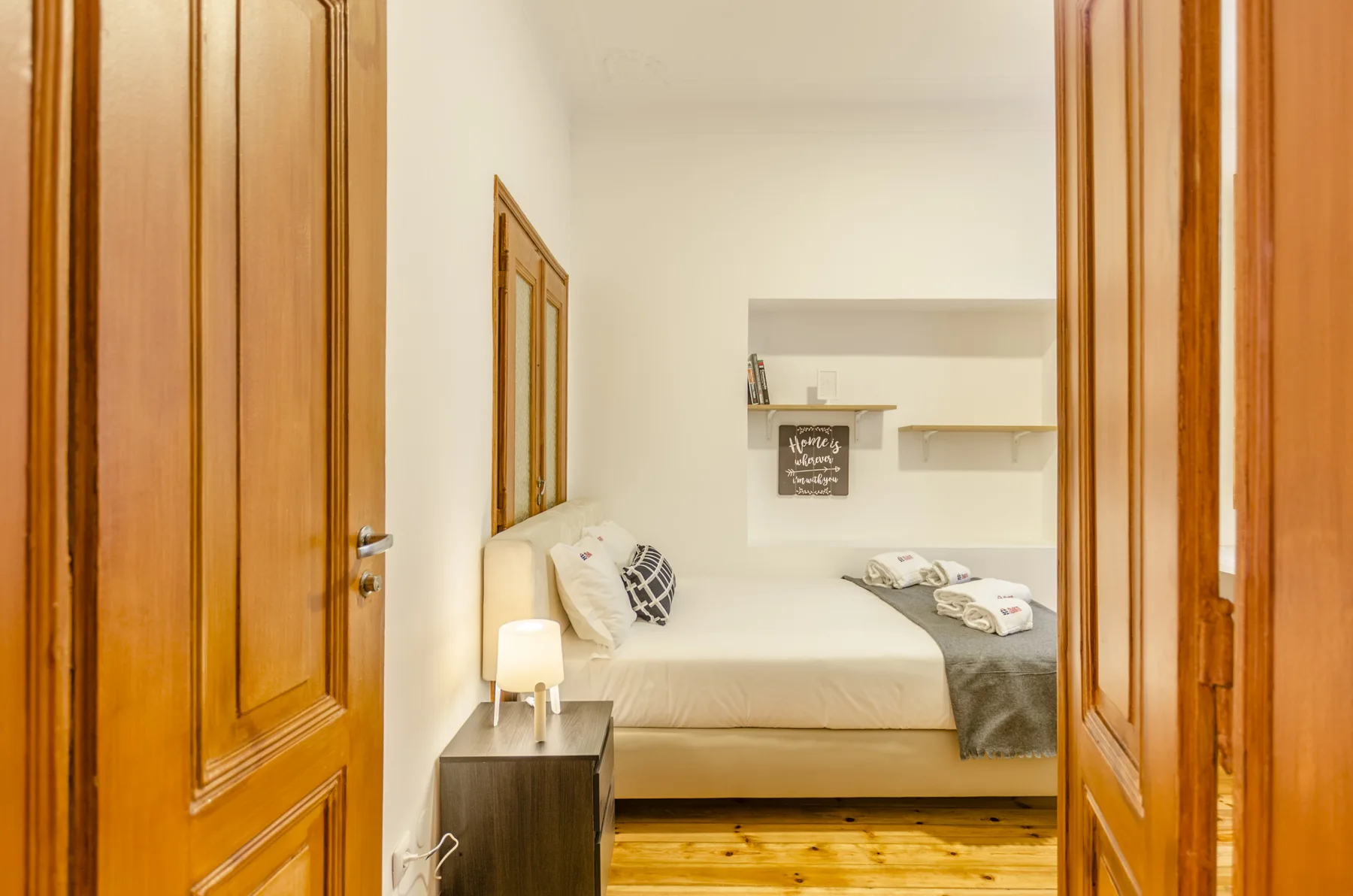 Un dormitorio con una cama, una mesita de noche y estantes empotrados.