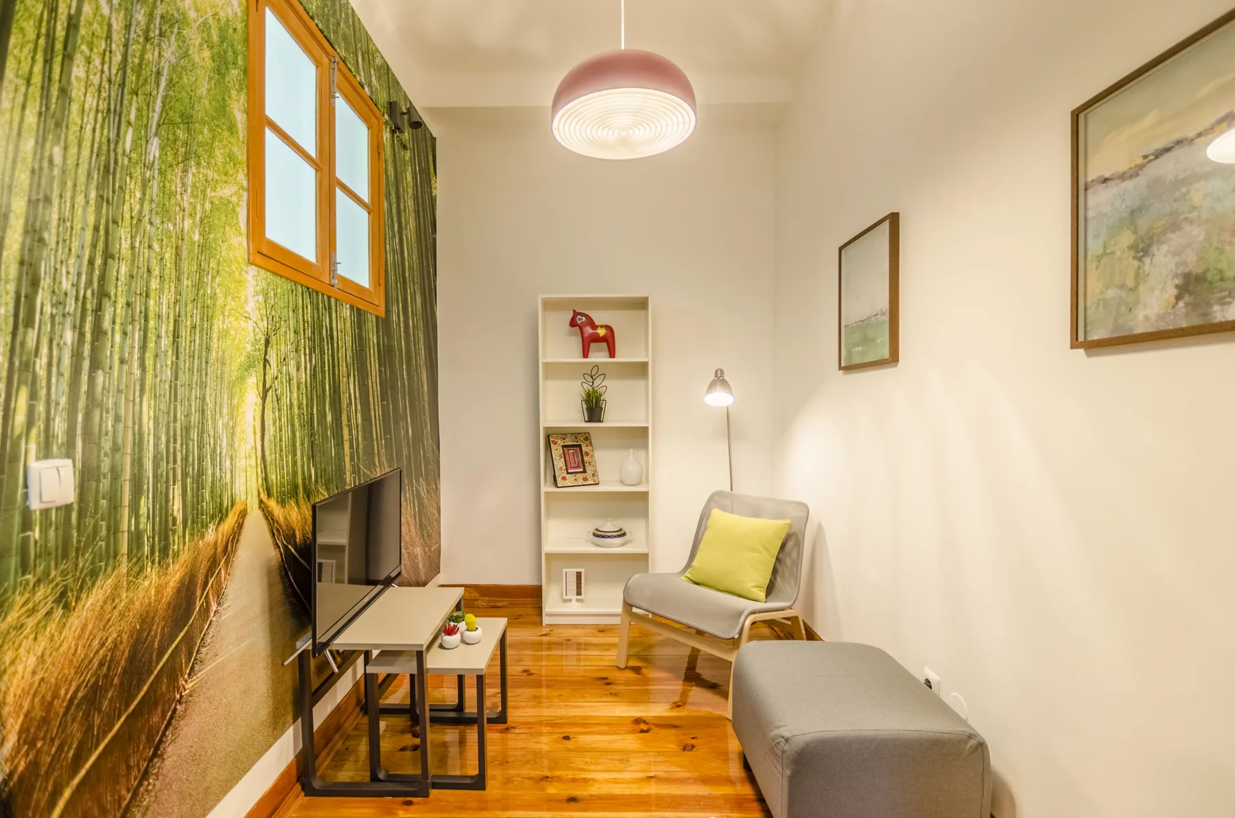 Una sala de estar con un mural, asientos y un televisor.