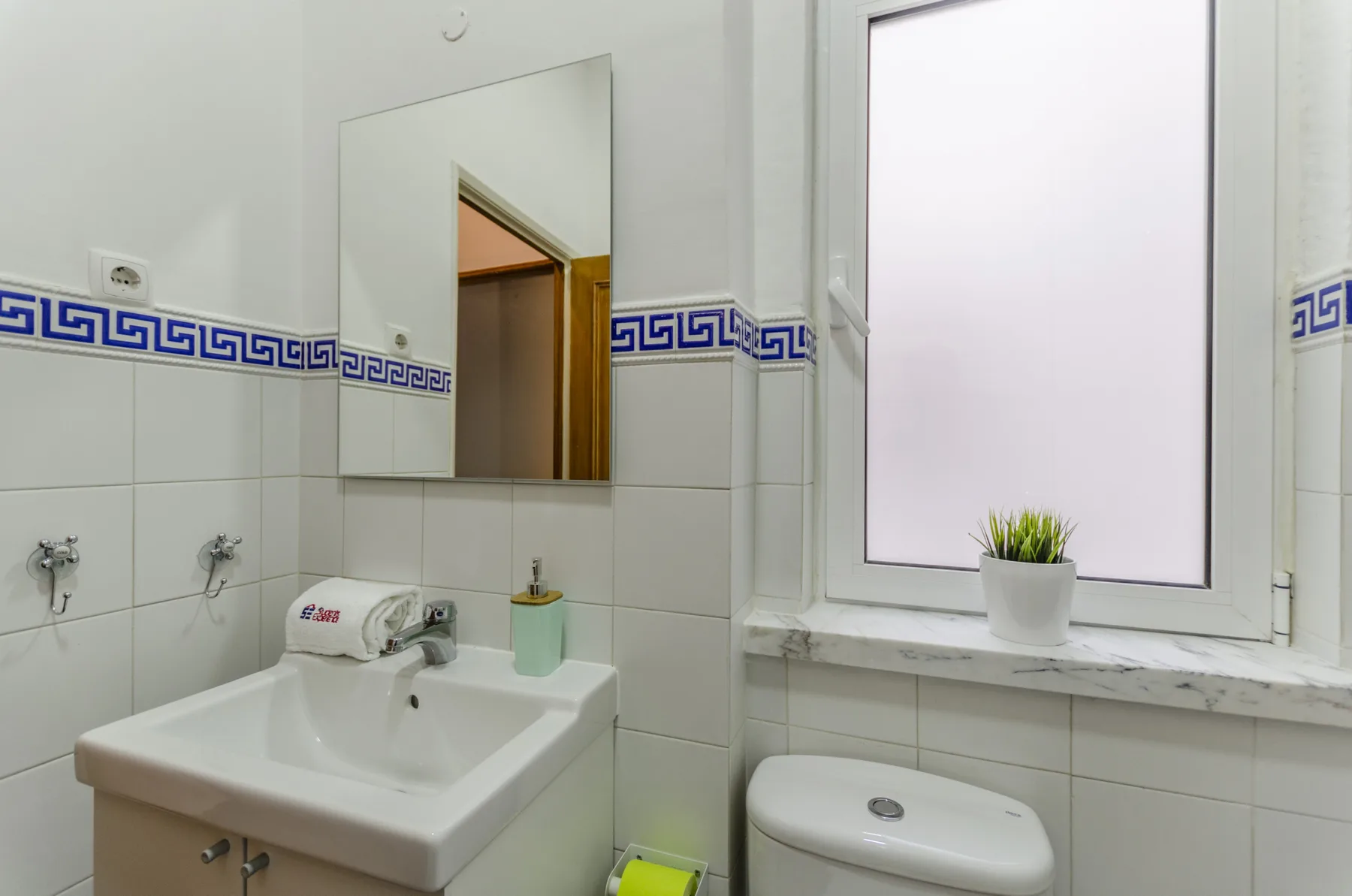 Un baño alicatado con lavabo, inodoro y ventana.