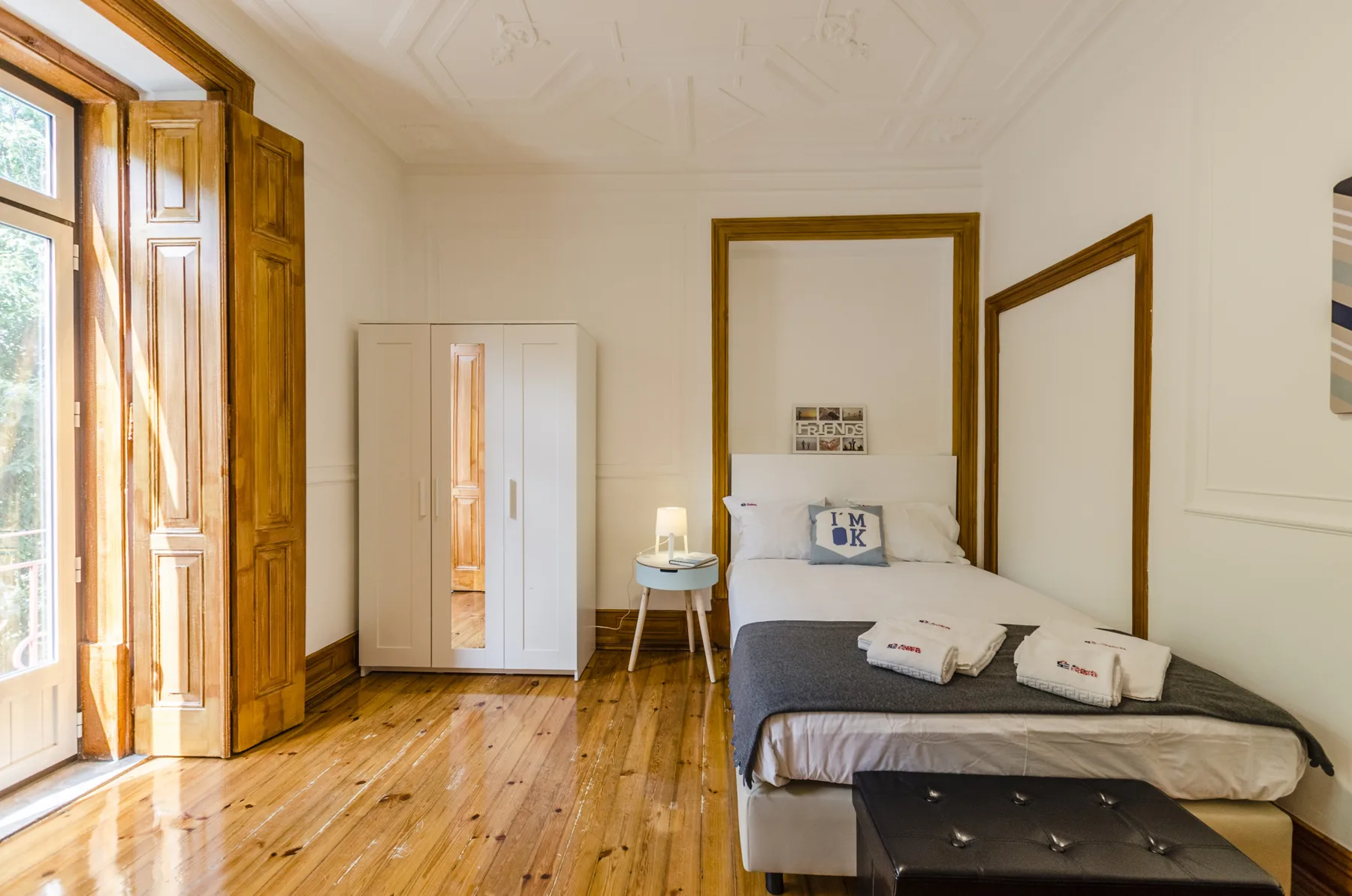 Un dormitorio con una cama, un armario y contraventanas altas de madera.