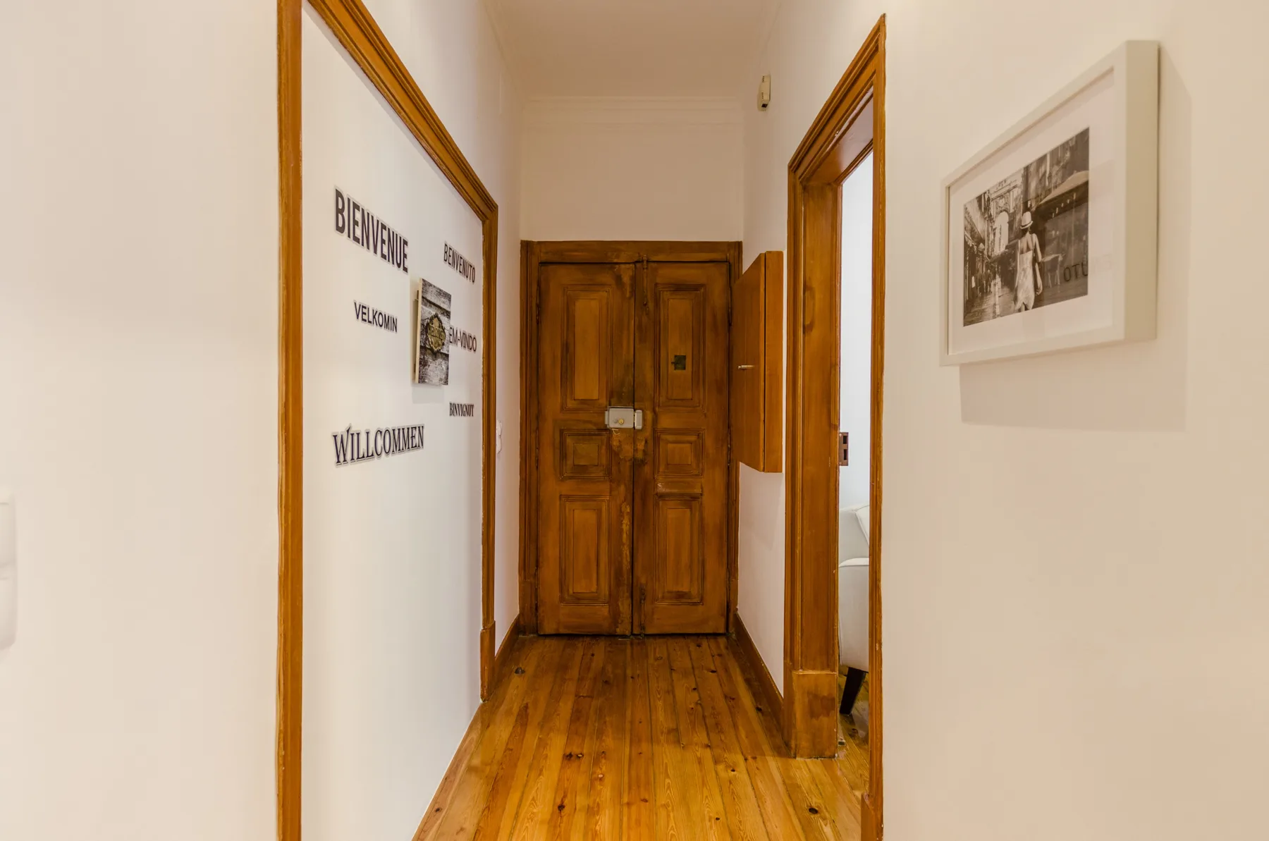 Un pasillo con suelo de madera conduce a una puerta de madera.