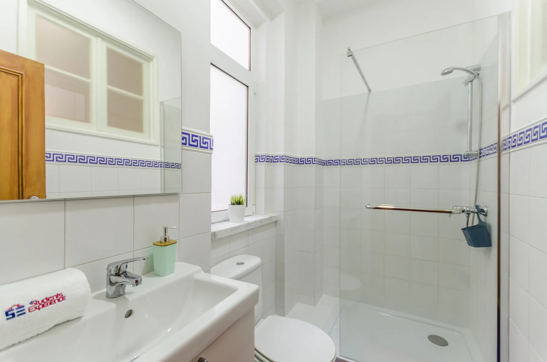 Un baño luminoso con lavabo y ducha con mampara de vidrio.
