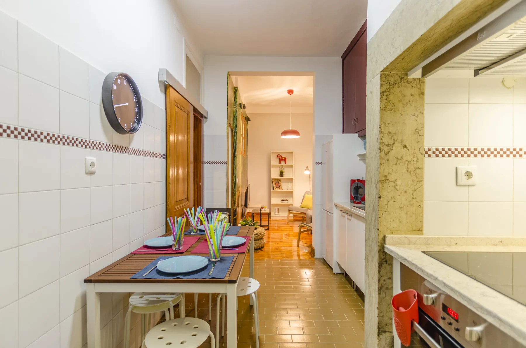 Una cocina alicatada con zona de comedor y una mesa preparada junto a la encimera.