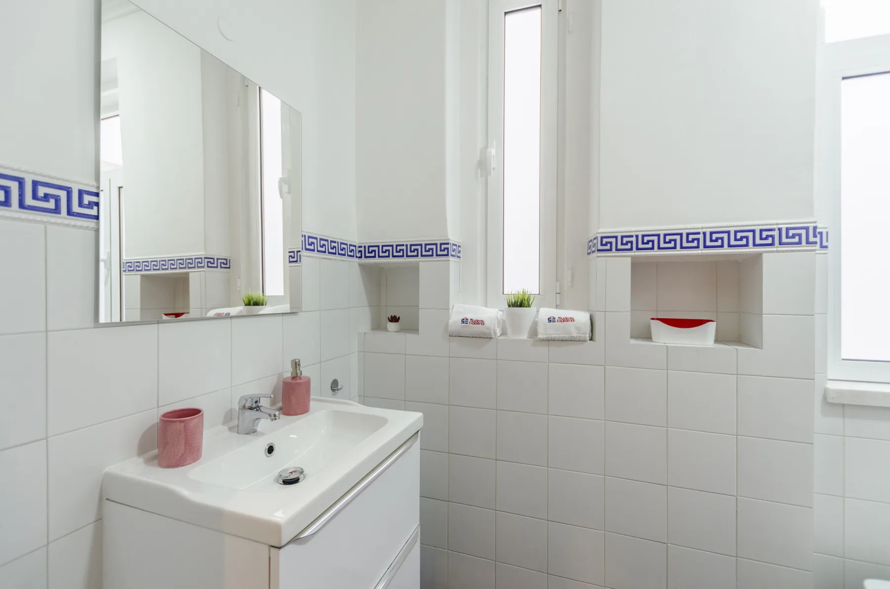 Un baño luminoso con lavabo, espejo y paredes de azulejos.
