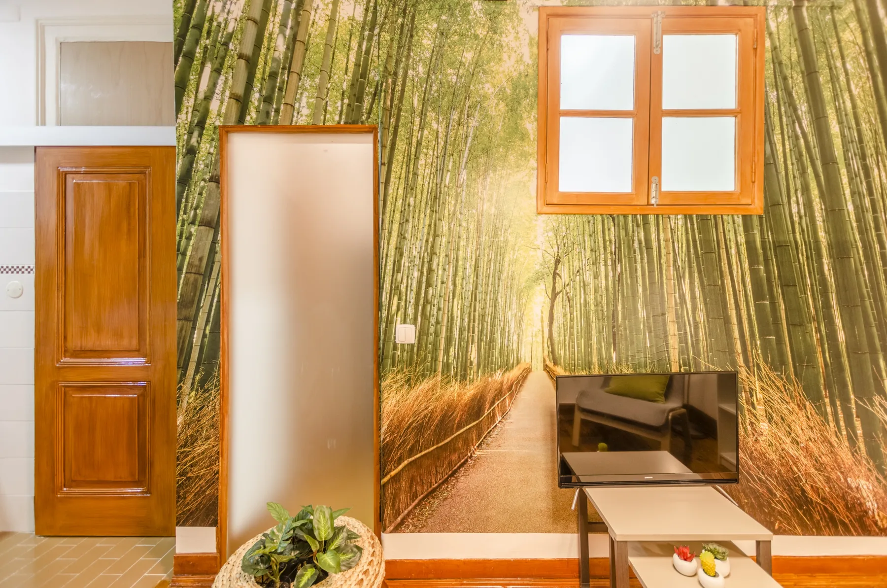 Una habitación con un revestimiento de pared con bambú, un televisor y una mesa pequeña.