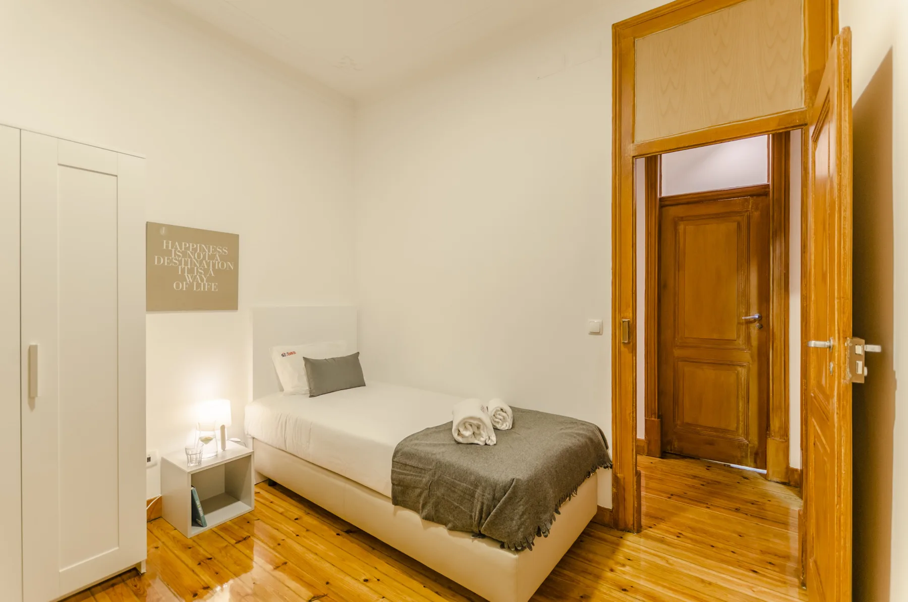 Un dormitorio con una cama bien hecha y una puerta de madera.
