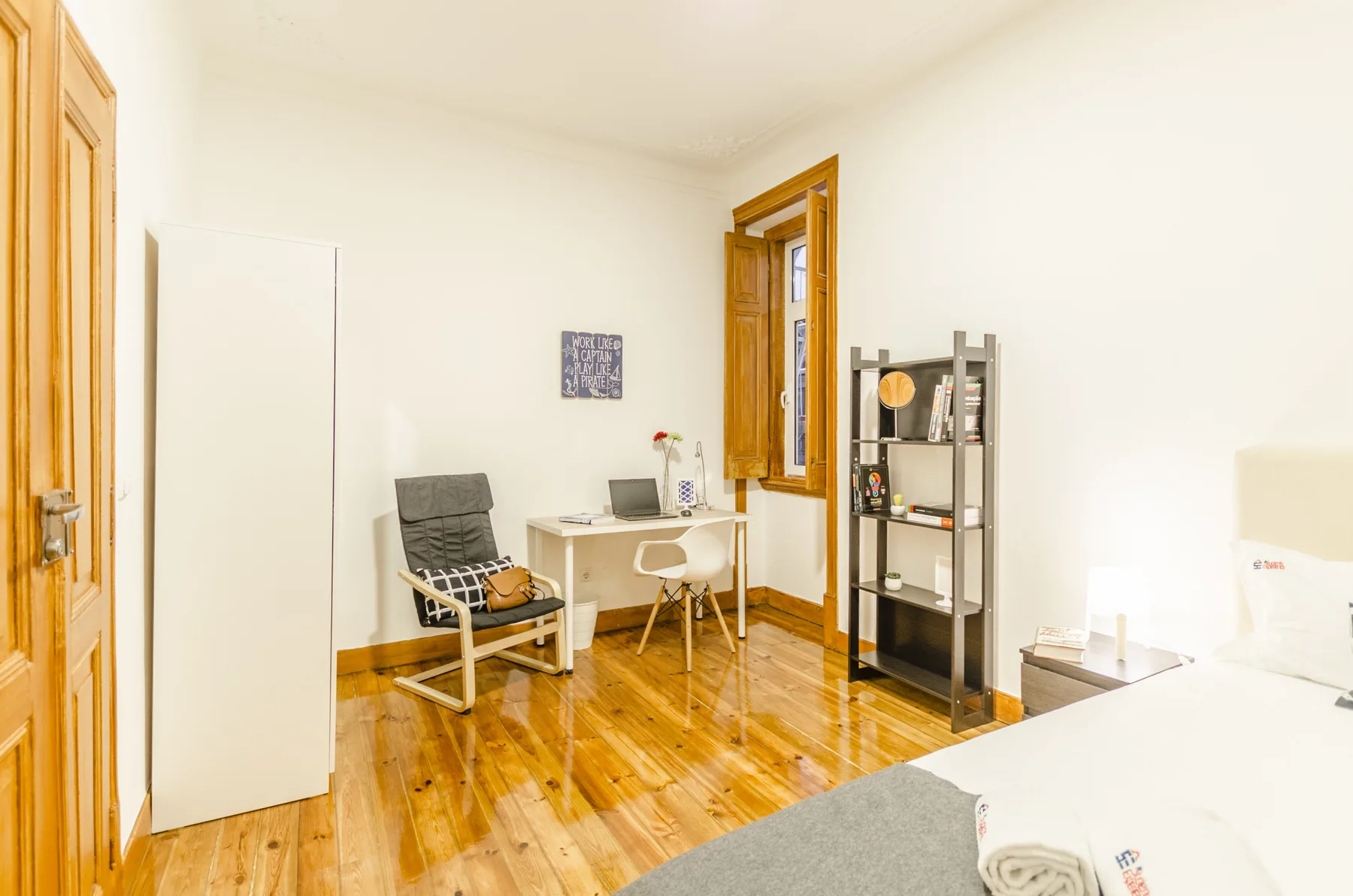 Una habitación luminosa con escritorio, asientos y una estantería alta.