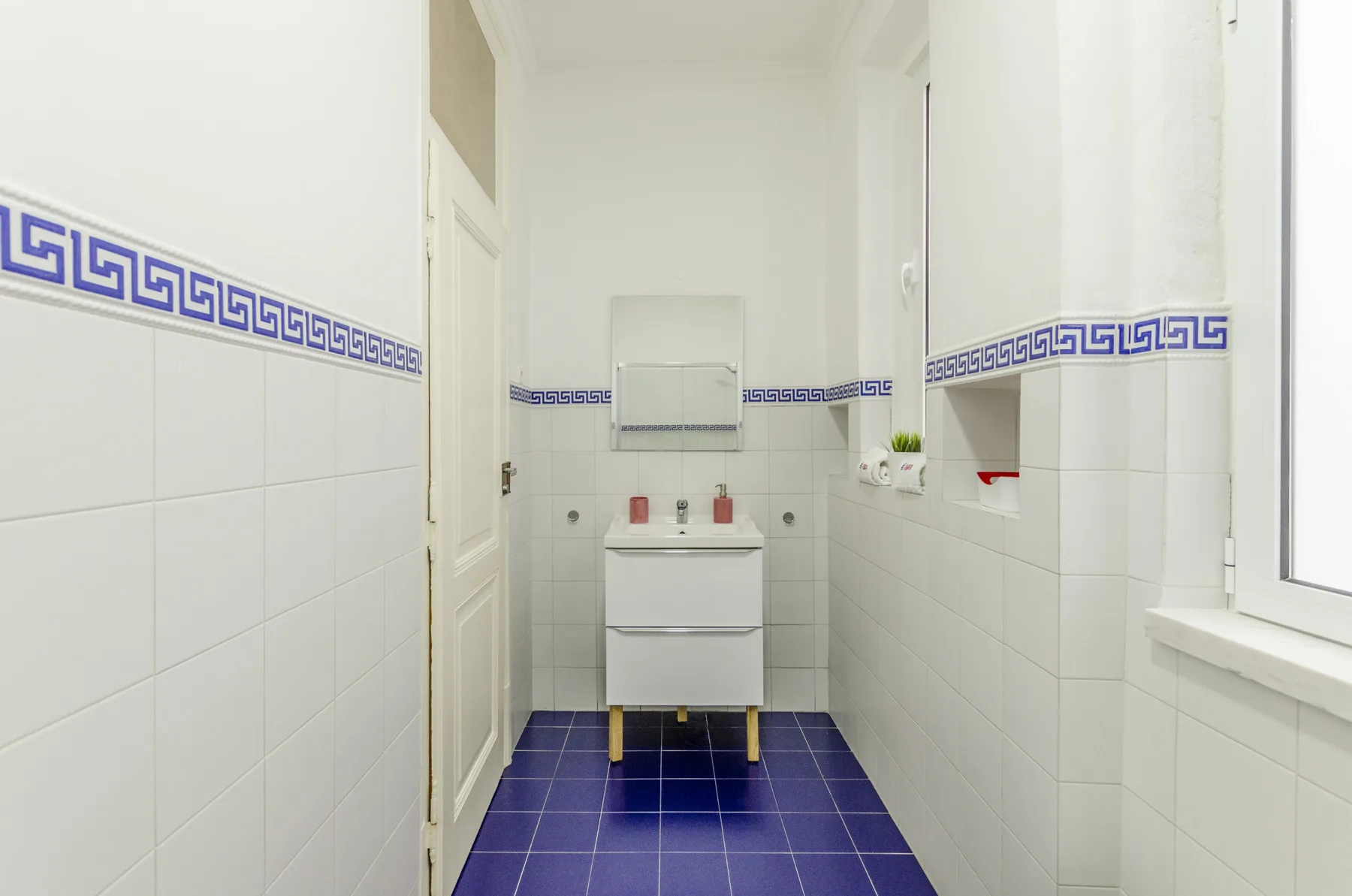 Un baño luminoso con lavabo y suelo de baldosas azules.