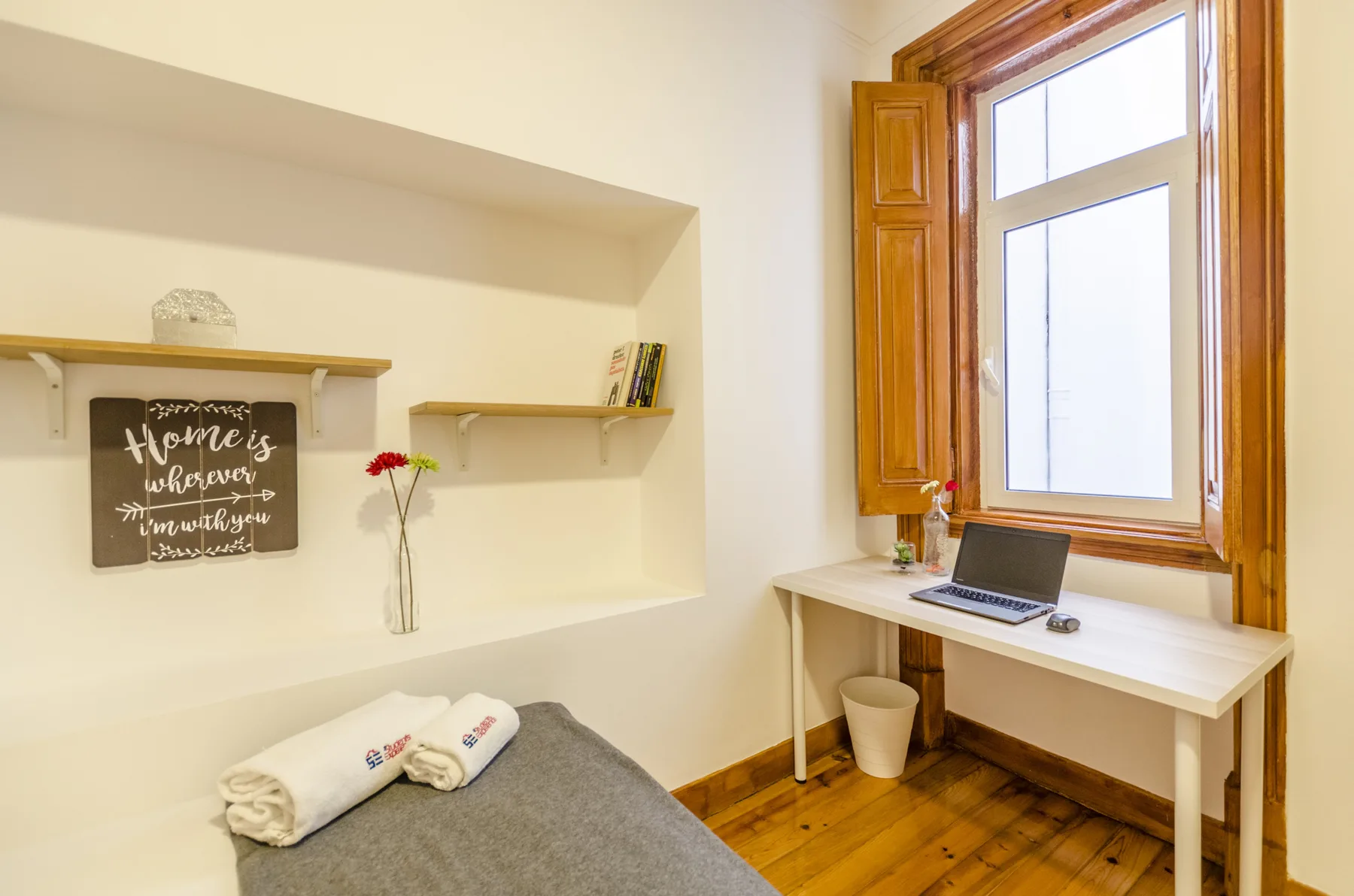 Dormitorio con un escritorio junto a una gran ventana con marco de madera.