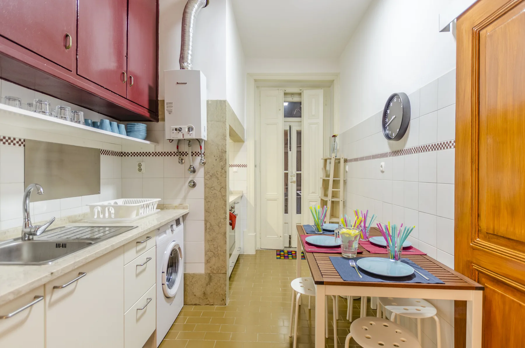 Una cocina estrecha con zona de comedor y una mesa preparada para comer.