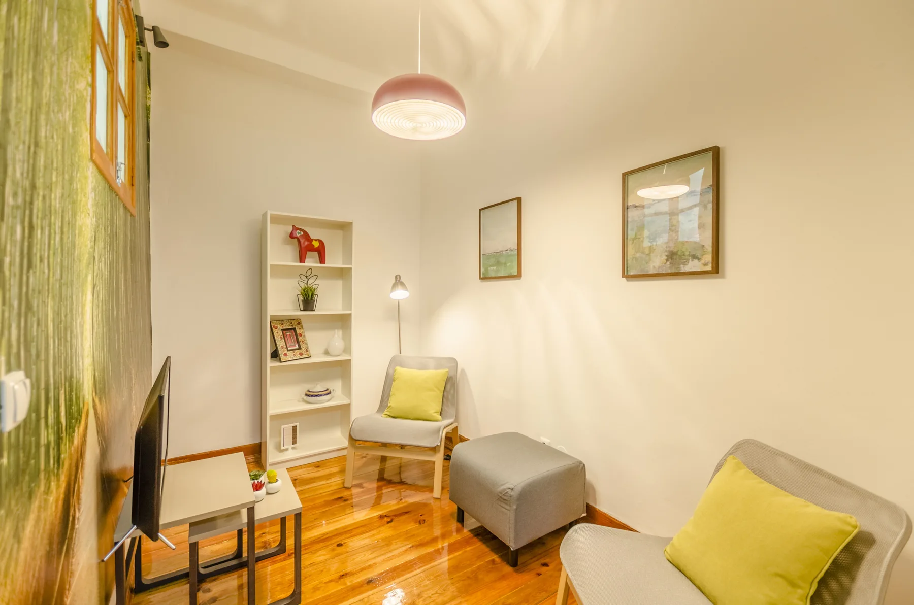 Una sala de estar con asientos, una mesa pequeña y una estantería.
