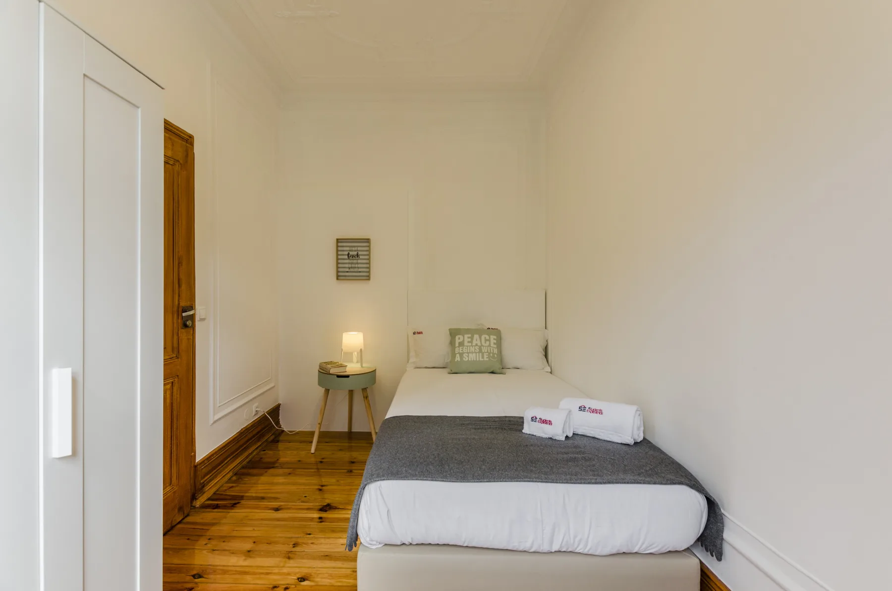 Un dormitorio con una cama, toallas dobladas y suelo de madera.