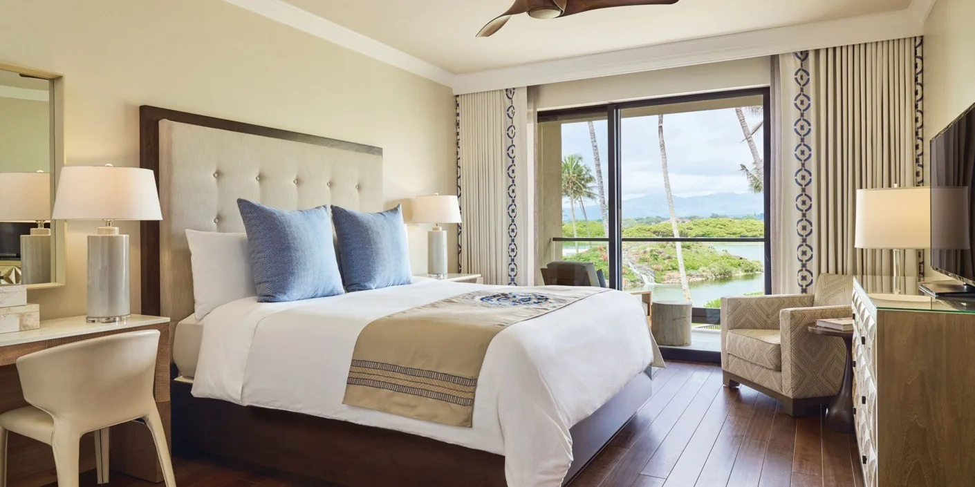 A bedroom with a large bed and sliding glass doors overlooking greenery and water.