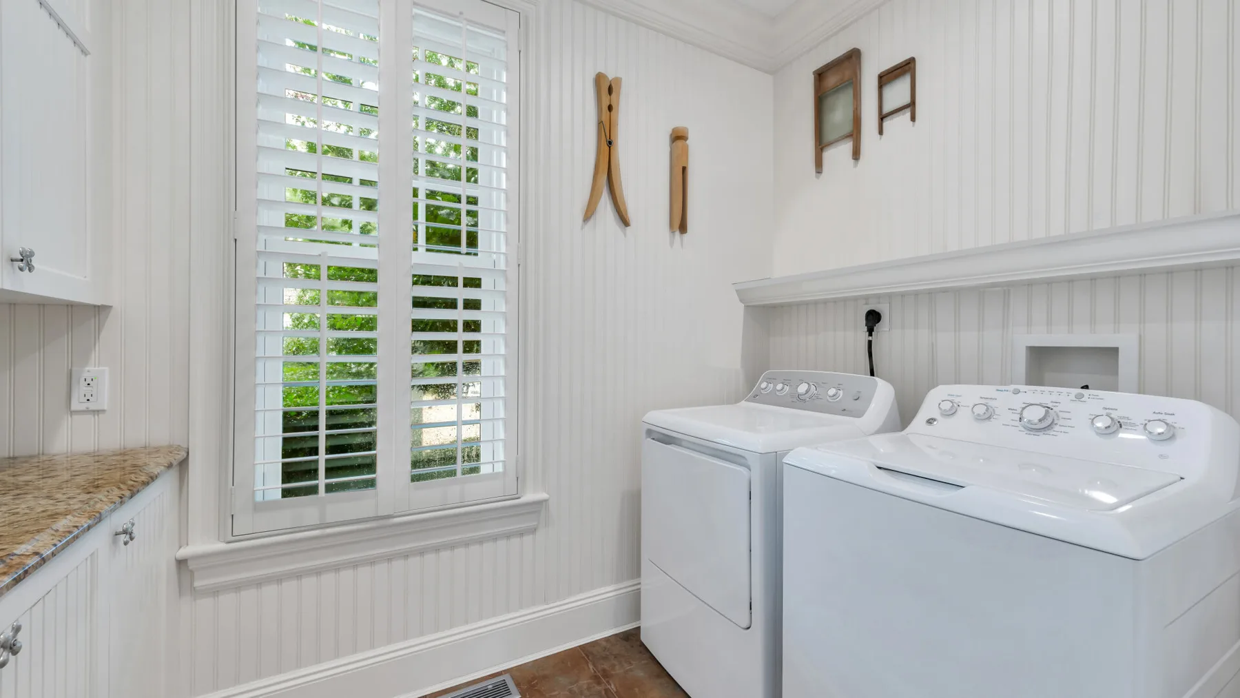 Un cuarto de lavado con lavadora y secadora junto a una ventana con persianas.