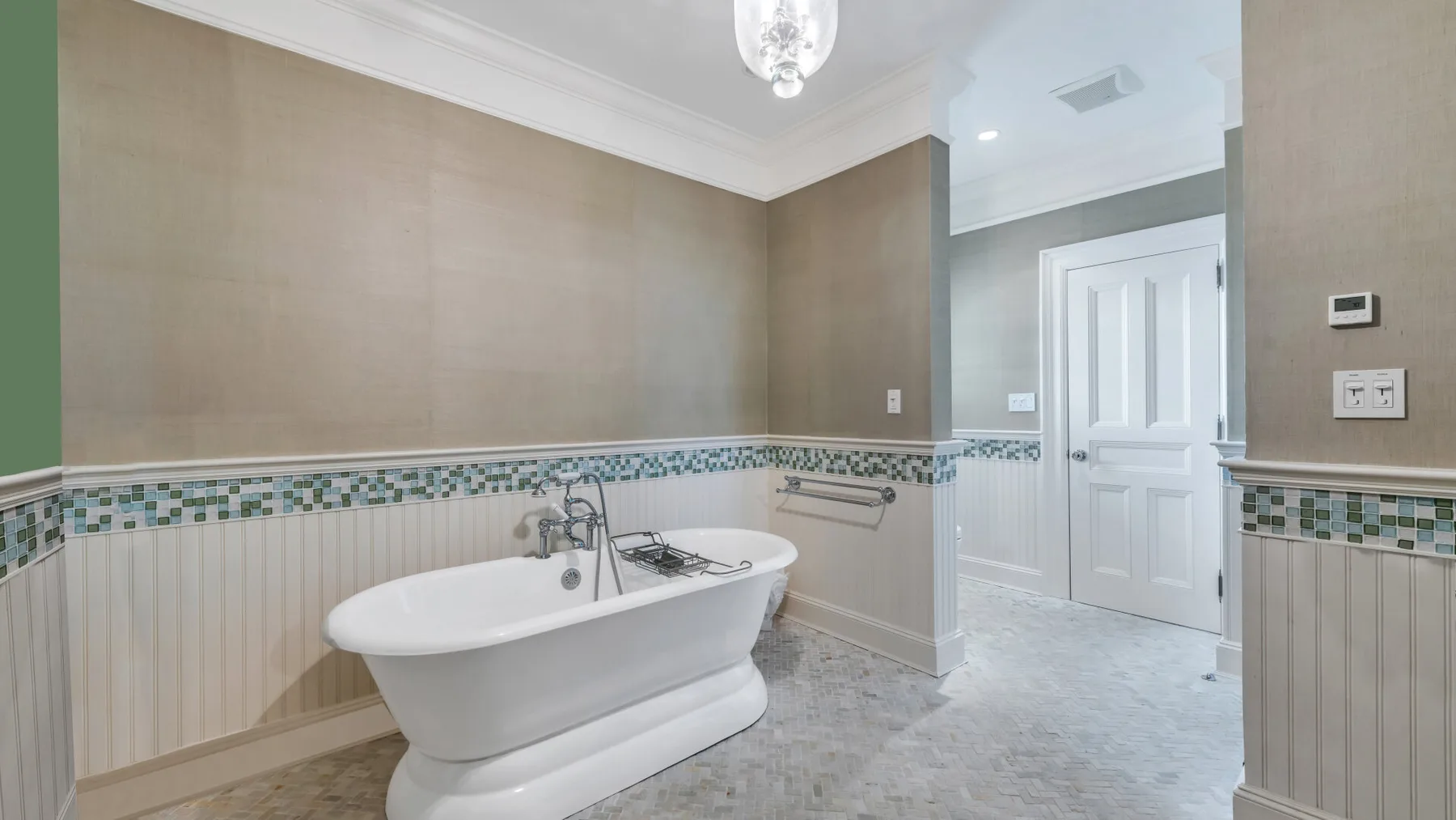 Un baño con una bañera exenta y una puerta blanca con paneles.