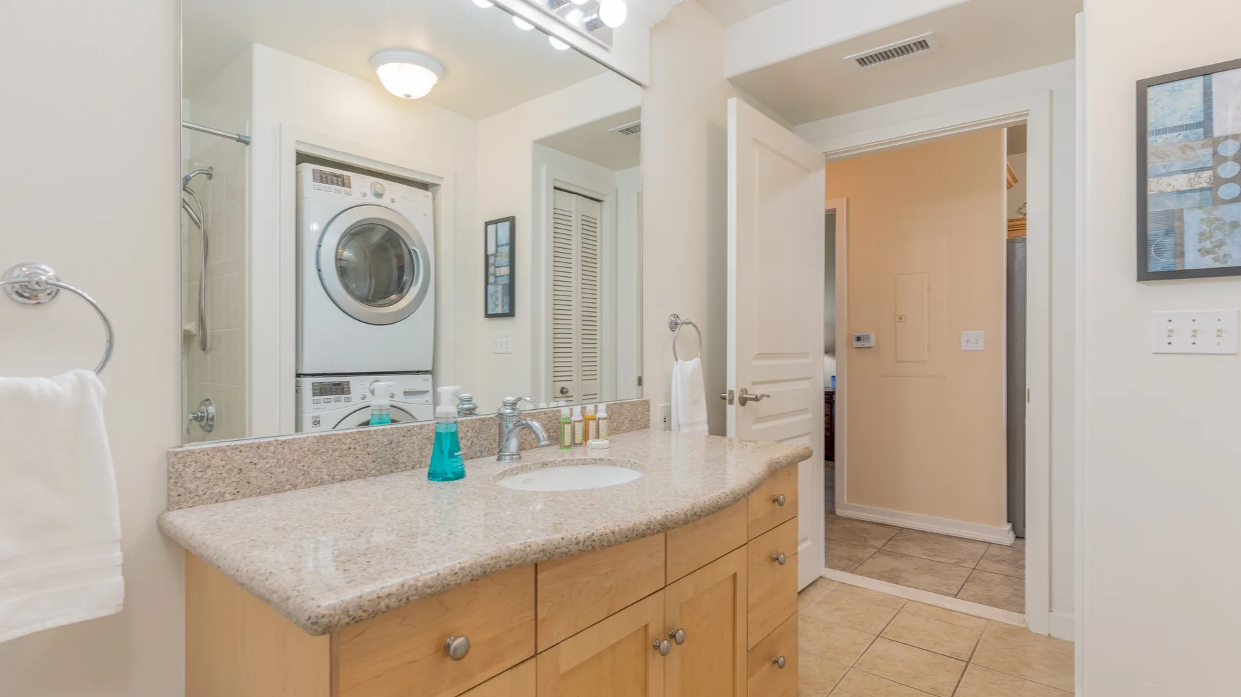 A bathroom vanity with a sink and a stacked washer and dryer.