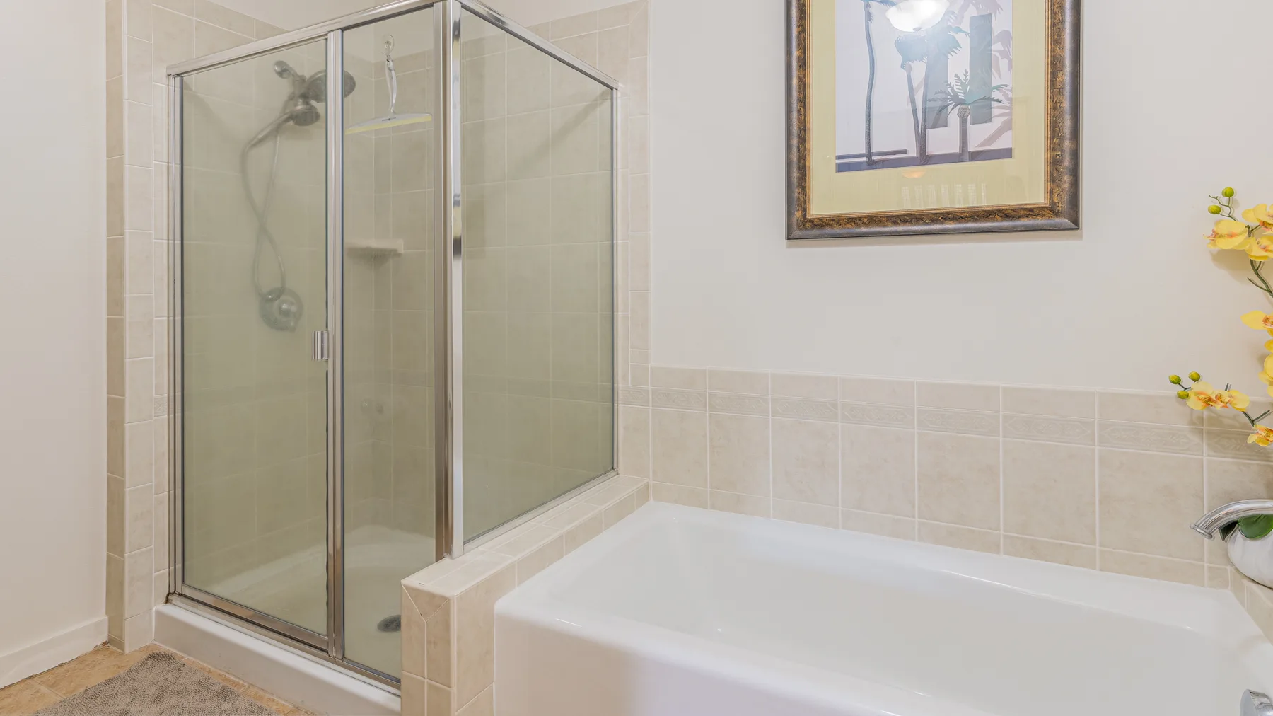 A tiled bathroom with a glass-enclosed shower and a bathtub.