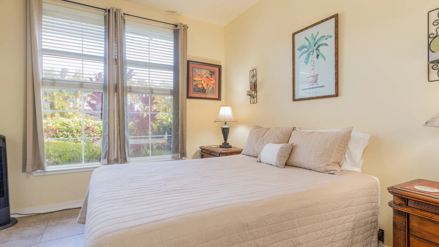 A bedroom with a bed, bedside table, and large windows.
