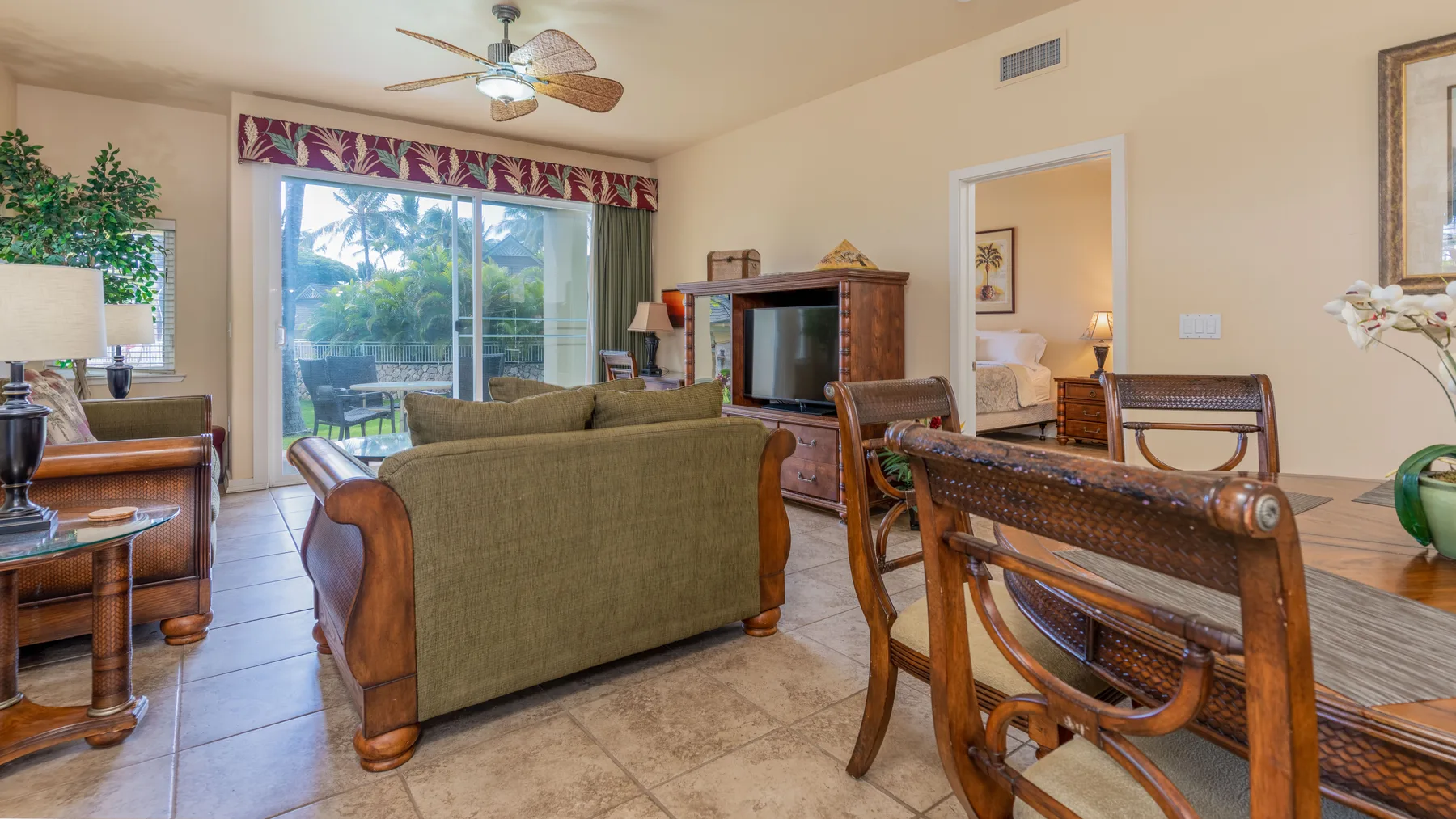 A living room with seating arranged around a television beside sliding glass doors.
