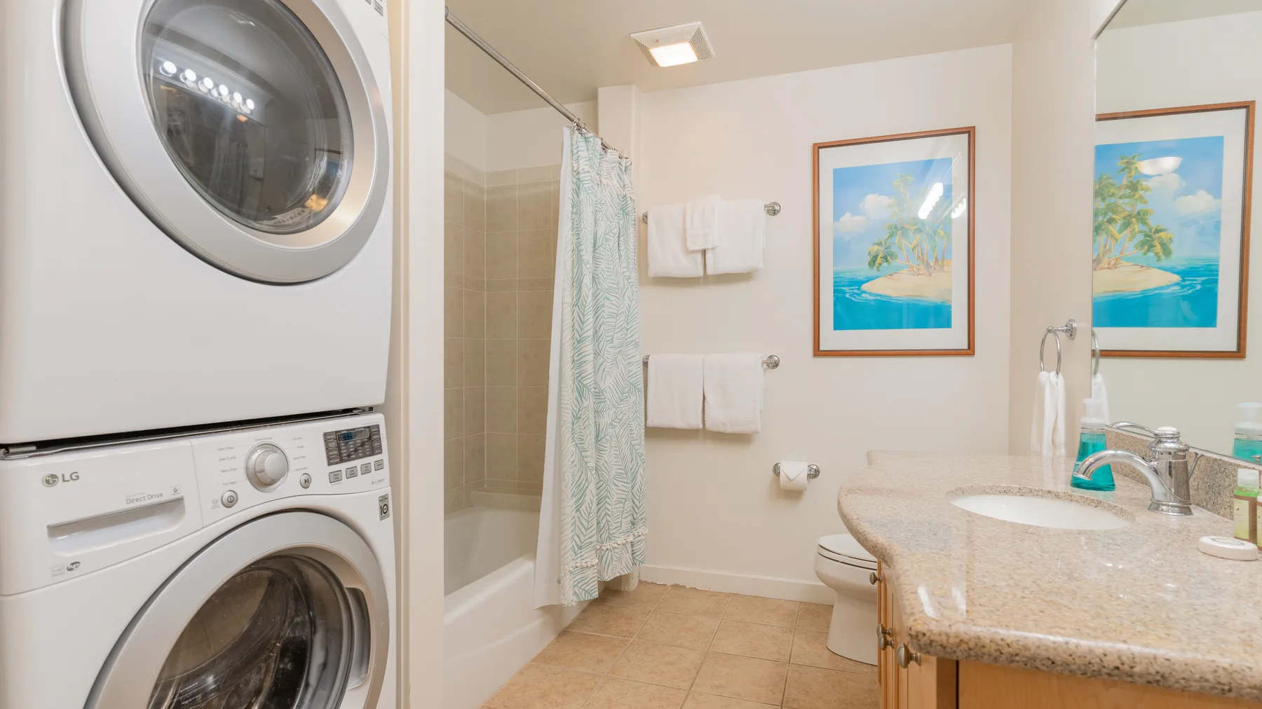 A bathroom with a sink, shower curtain, and stacked laundry machines.