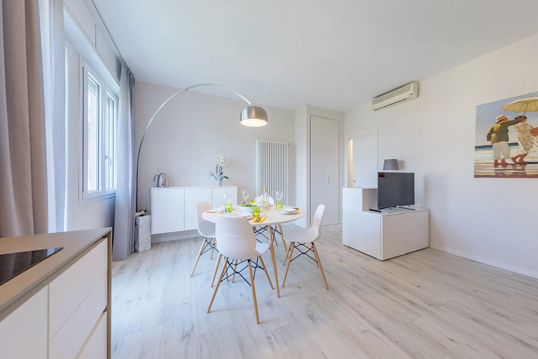 A bright dining and living area with a table, seating, and a television.