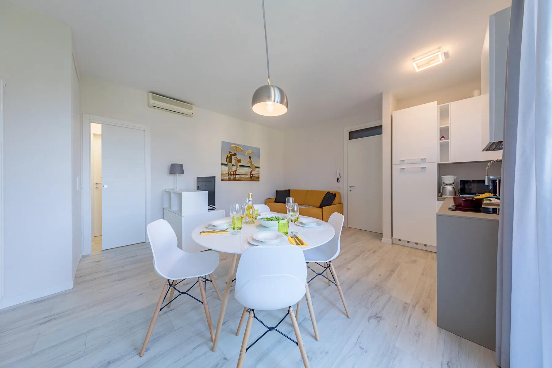 A bright dining area with a set table and a kitchen along one side.