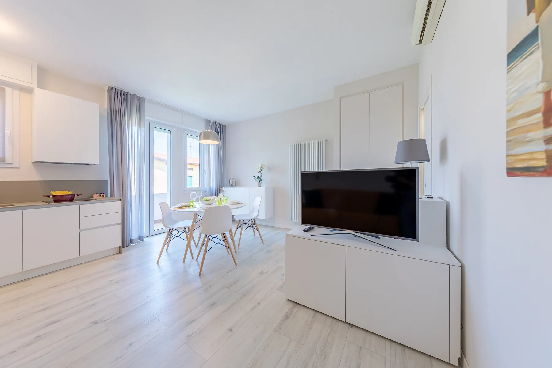 A bright living and dining area with a table, seating, and a television.