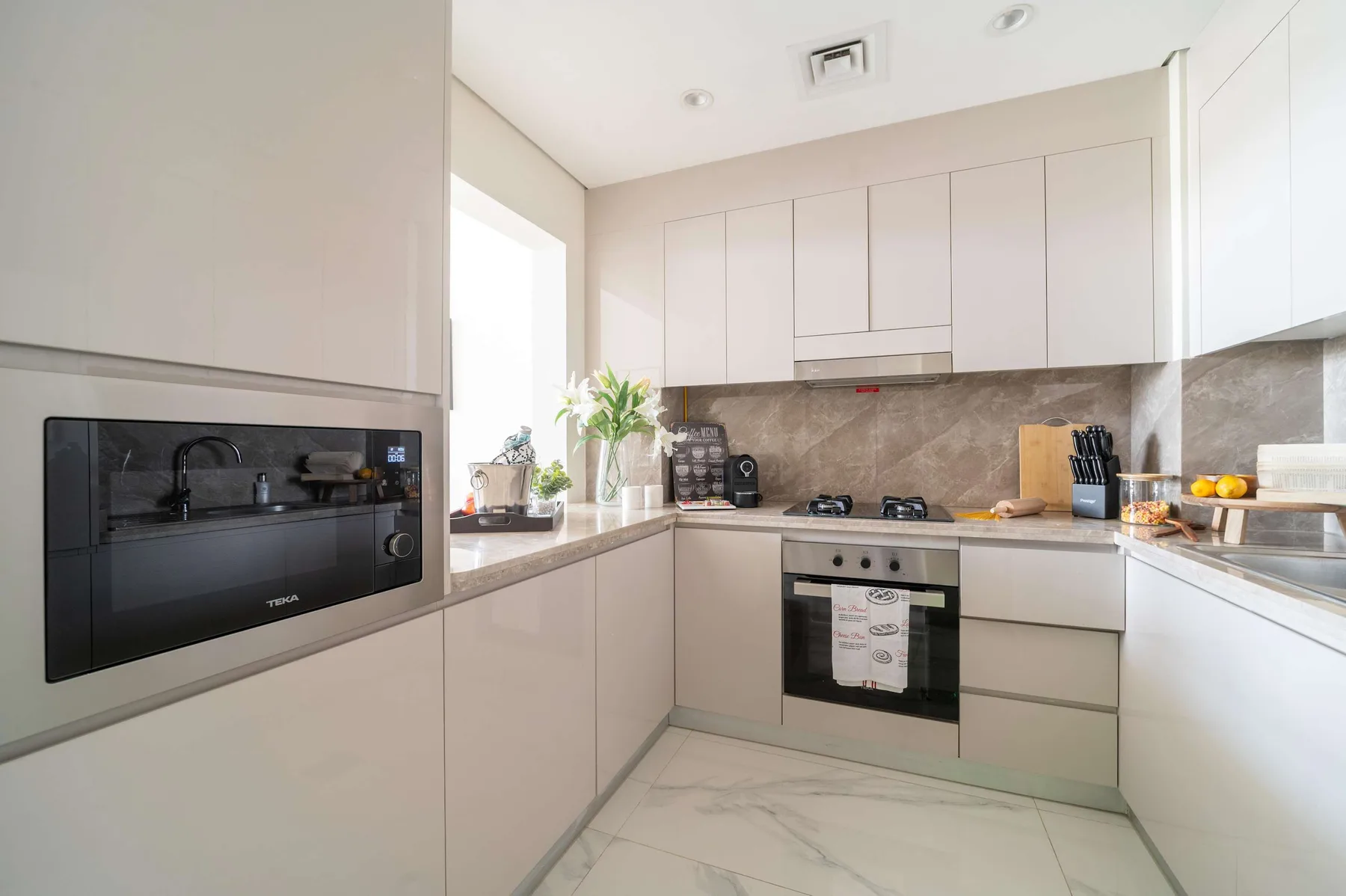 Una cocina moderna y luminosa con gabinetes claros, una estufa y un horno.