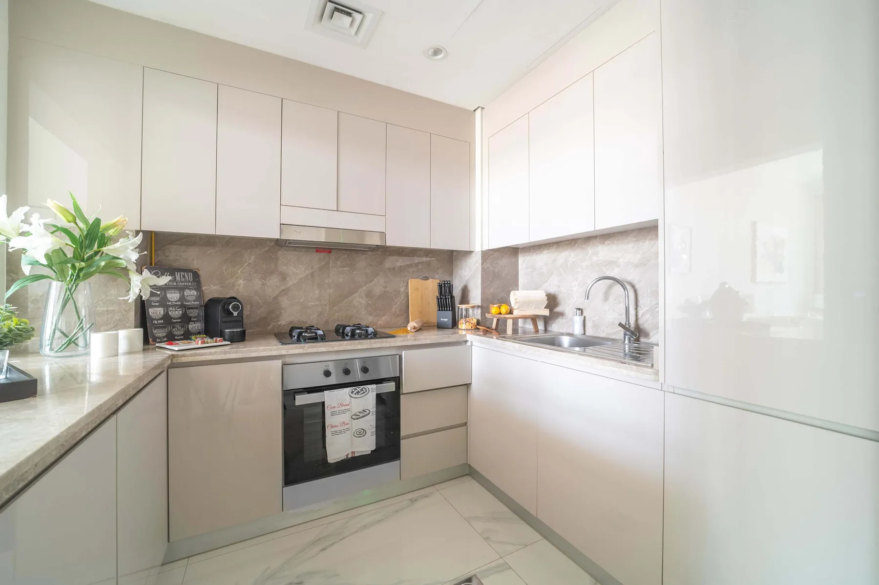 Una cocina moderna y luminosa con gabinetes blancos, encimera y horno empotrado.