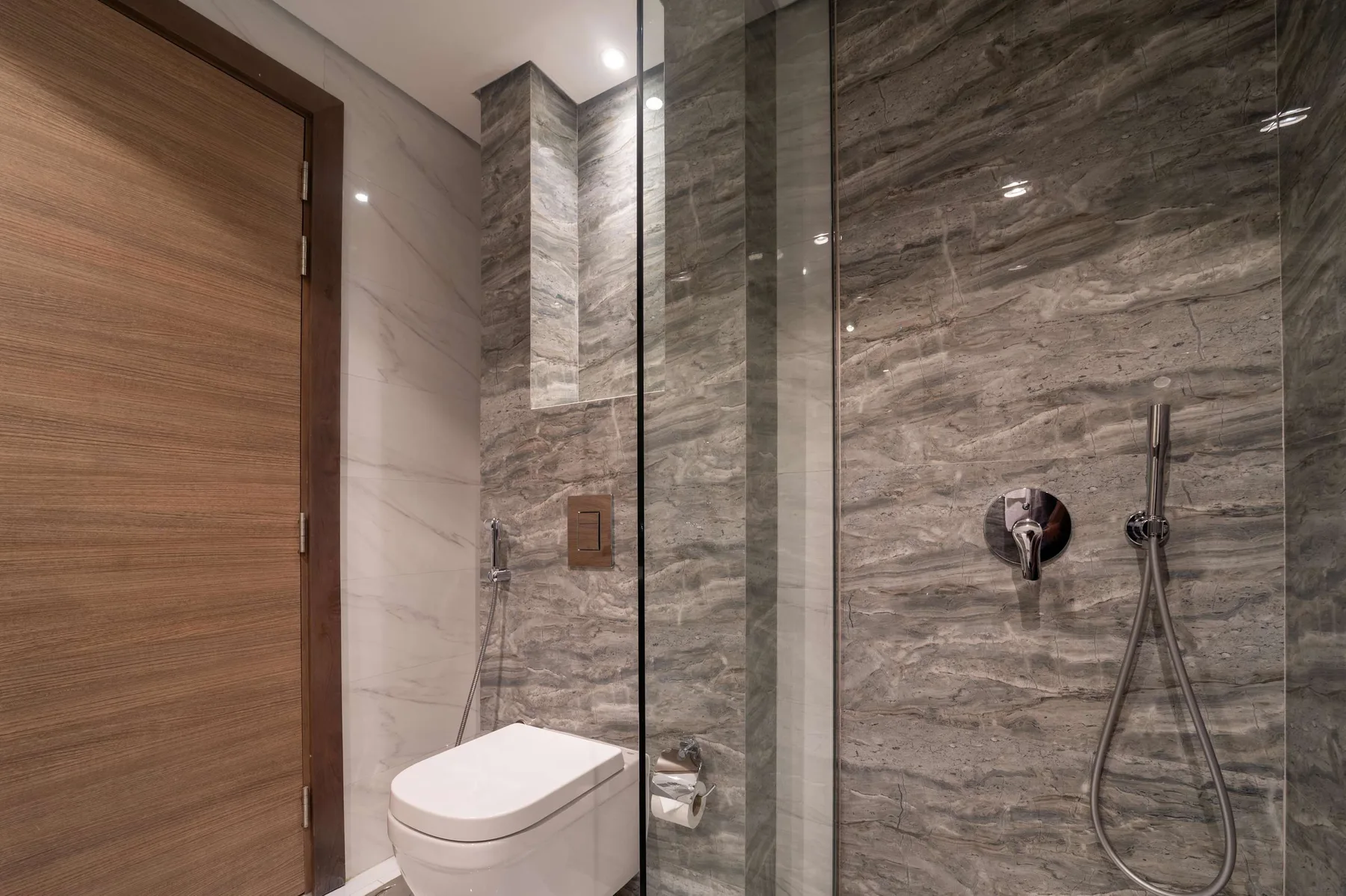 Un baño moderno con un inodoro junto a una ducha de vidrio.