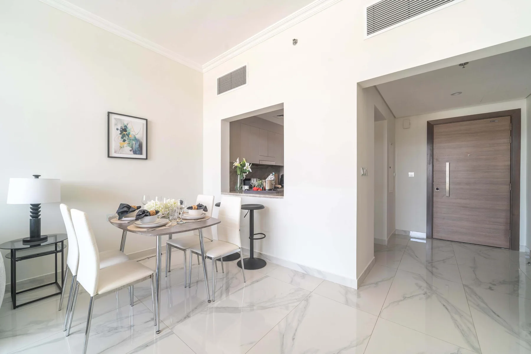 Un comedor luminoso con una mesa, asientos y una abertura hacia la cocina.