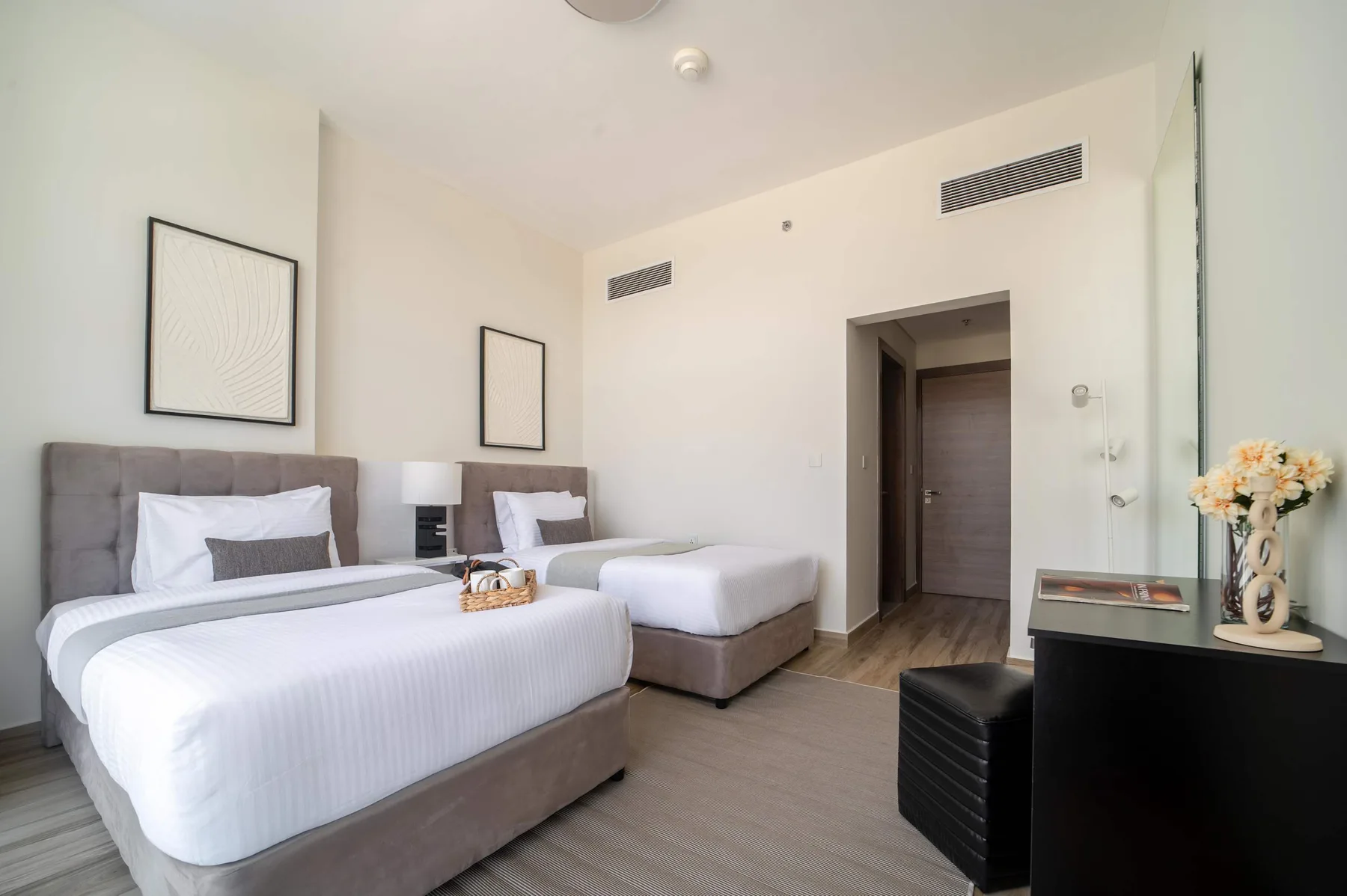 Un dormitorio luminoso con dos camas y cuadros en las paredes.