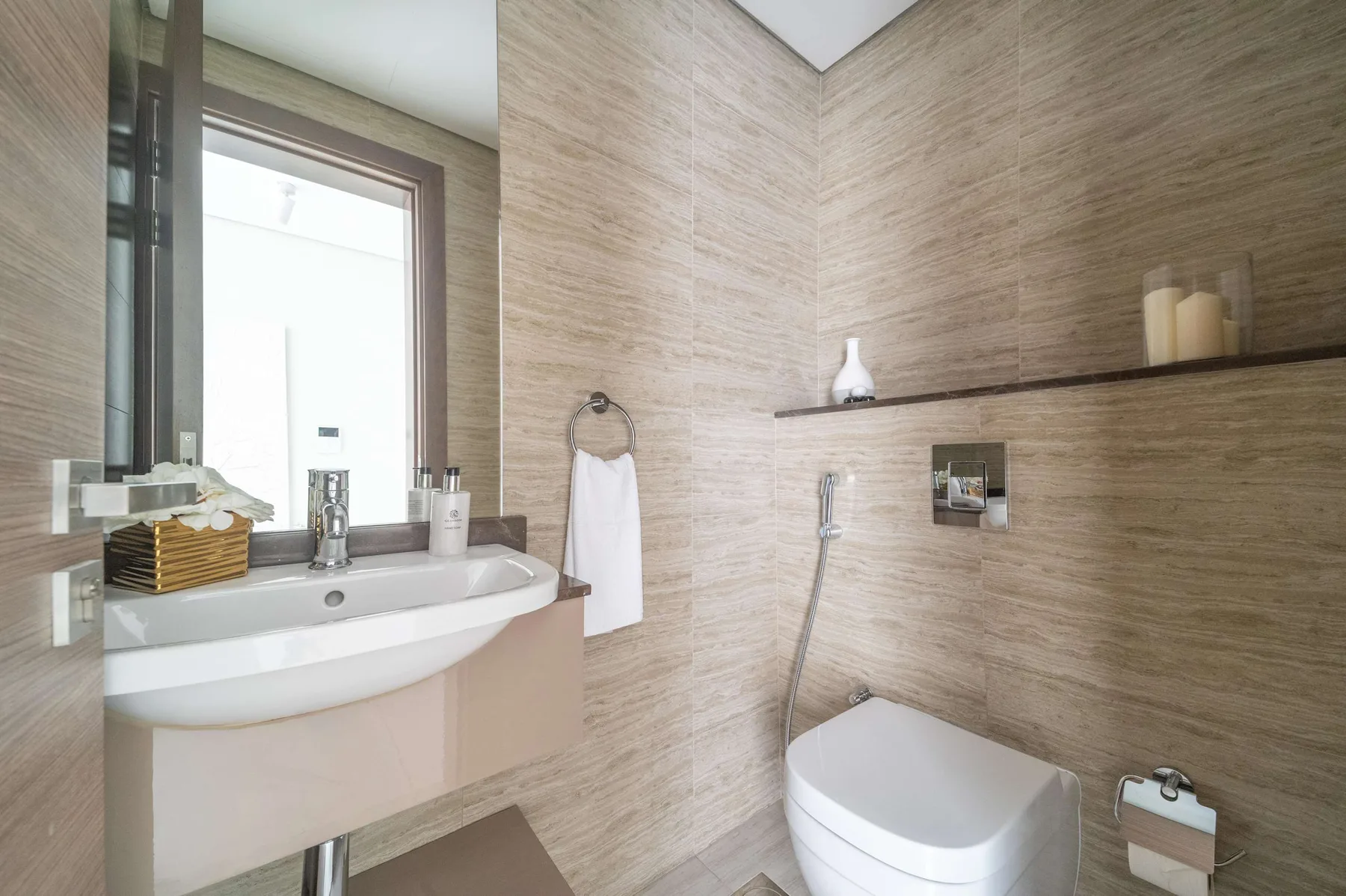 Un baño revestido de azulejos con lavabo, espejo y accesorios de ducha.
