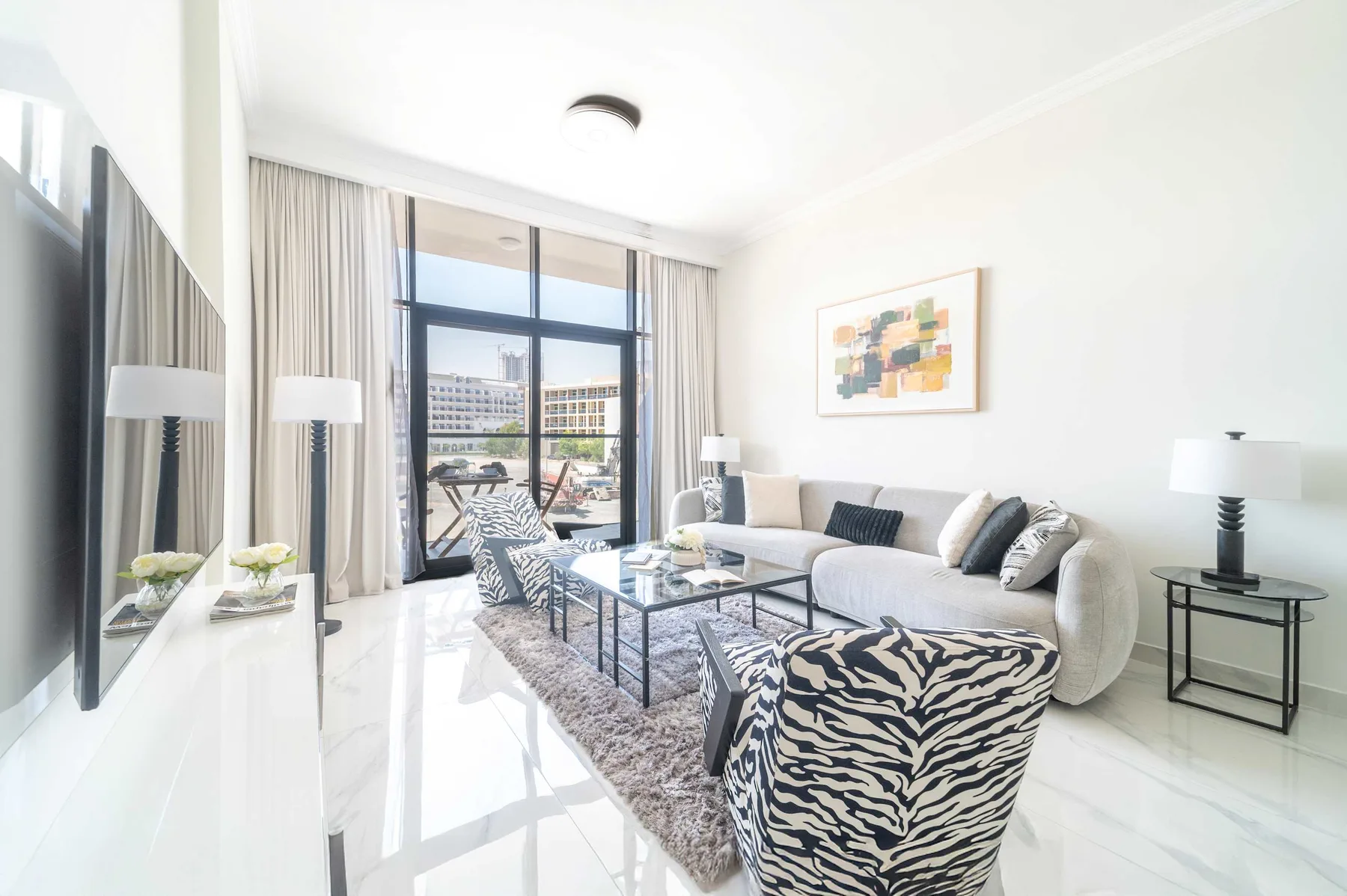 Una luminosa sala de estar con zona de descanso y grandes puertas de vidrio hacia un balcón.