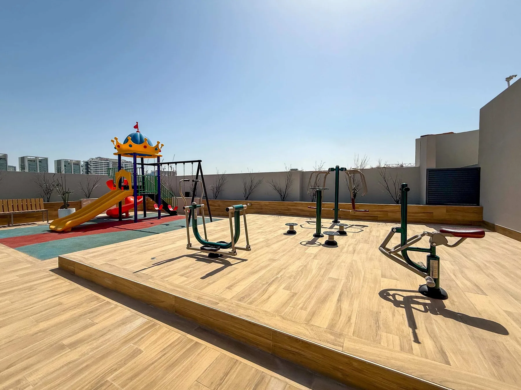 Una zona recreativa en la azotea cuenta con un parque infantil colorido y equipos de ejercicio al aire libre.