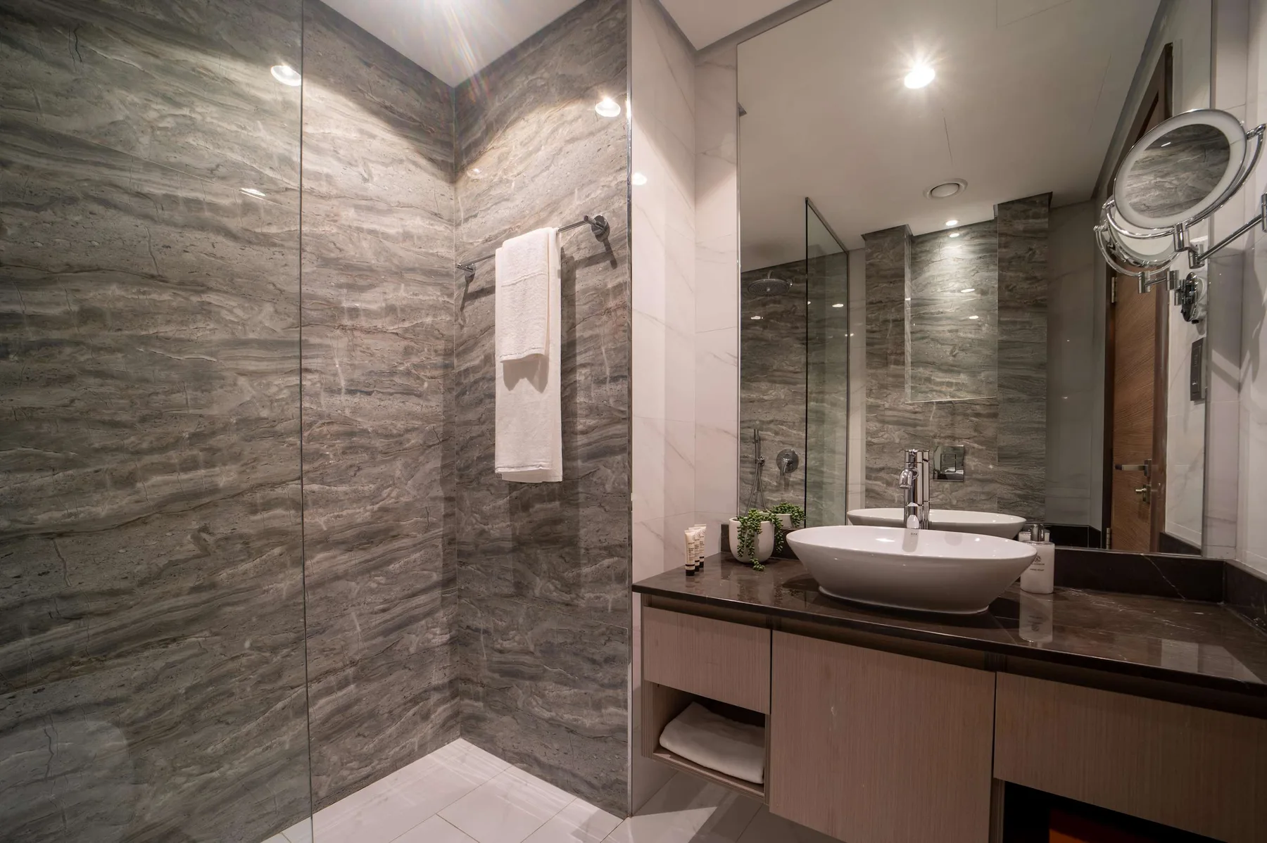 Un baño moderno con tocador, lavabo y zona de ducha con vidrio.