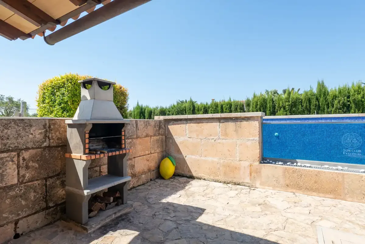 An outdoor patio with a built-in barbecue beside a swimming pool.