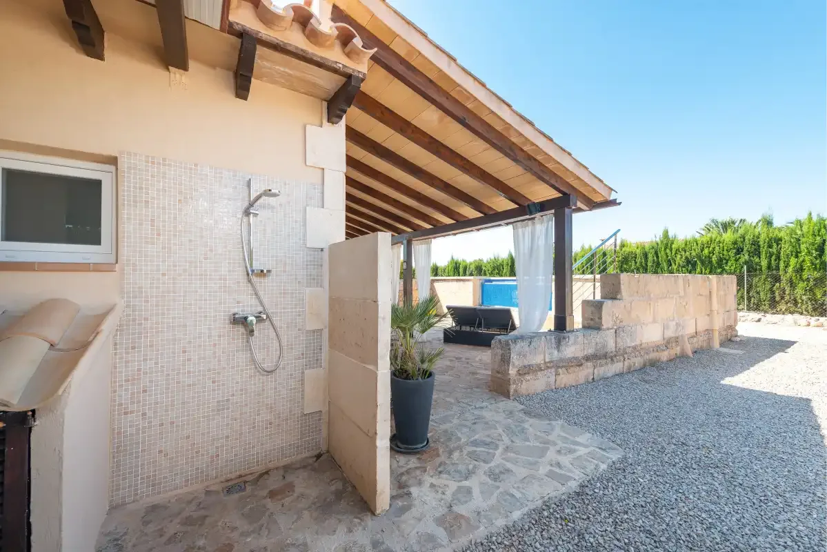 An outdoor shower area opens onto a gravel courtyard with a small pool.