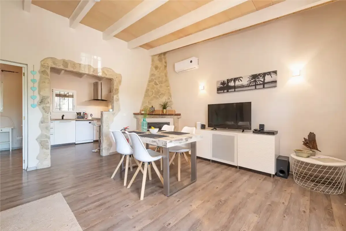 A dining and living area with a table, seating, and a television.