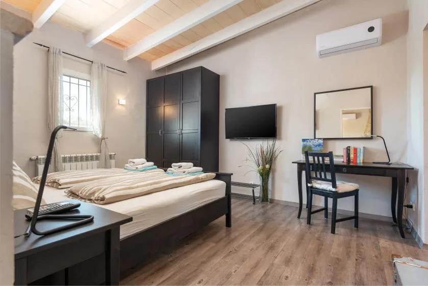 A bedroom with a bed, a desk, and a television.