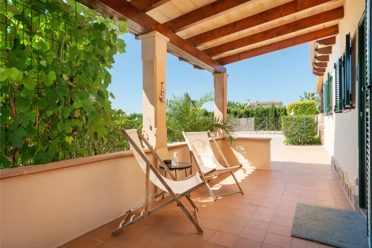 A covered terrace with seating overlooks a sunny garden.