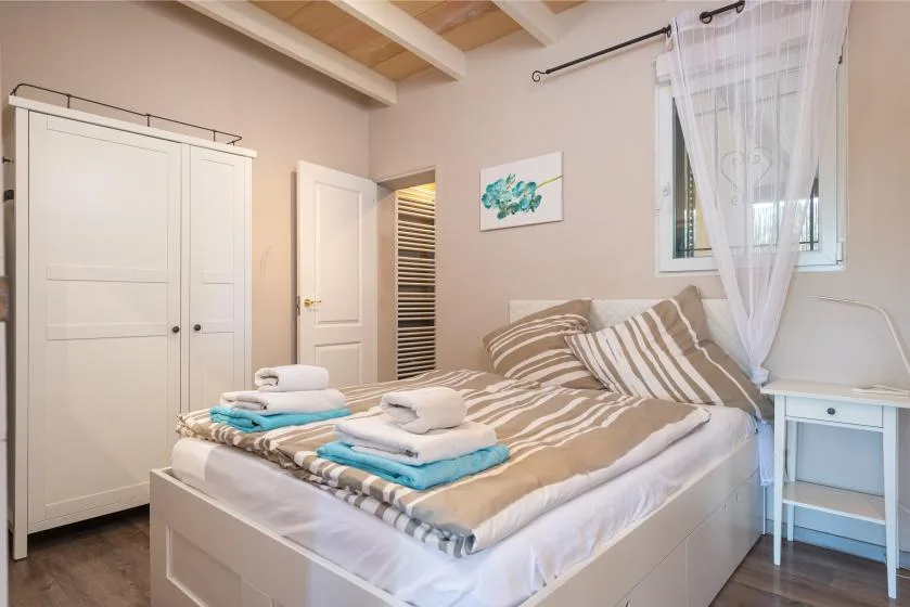 A bedroom with a neatly made bed and folded towels.