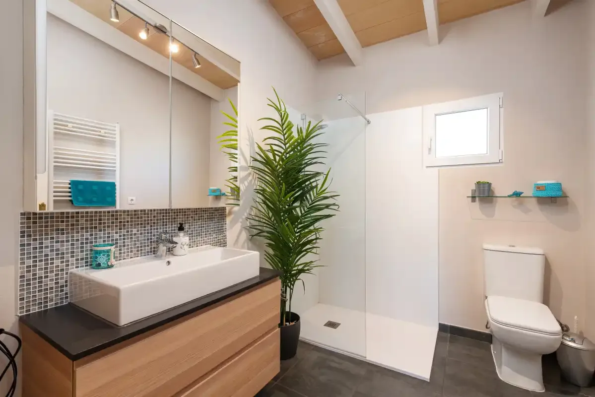 A bright bathroom with a wide vanity, shower, and toilet.